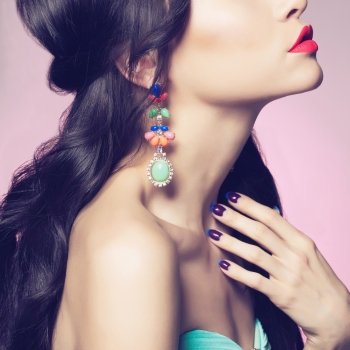 Fashion studio portrait of beautiful young woman with earring. Beauty and manicure. Jewelry and accessories