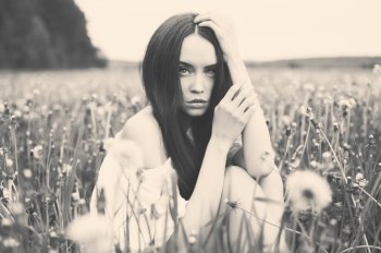 Black and white outdoors art photo of beautiful lady in dandelions field