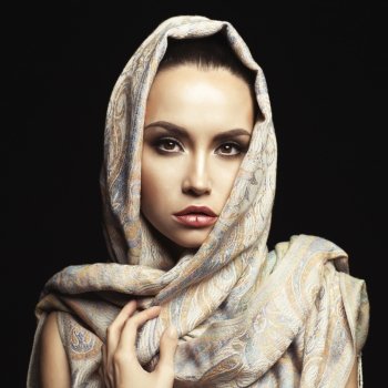 Studio fashion portrait of beautiful lady wrapped in a orient shawl