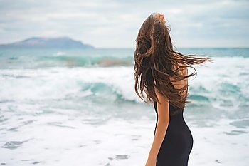 Outdoor photo of beautiful young woman walking at the sea