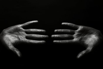 beautiful male hands in silver paint on black background