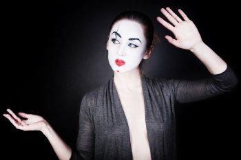 A woman in a theatrical mime make-up dancing on a black background