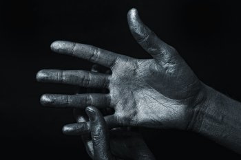 Men’s hand in a silver paint isolated on black background
