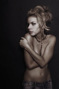 Studio portrait of young beautiful nude blonde woman on black background