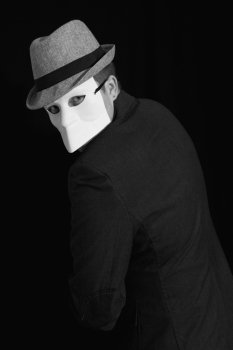 Portrait of a man wearing a suit and white masquerade mask 