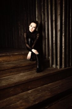 Portrait of a young woman sitting on wooden stairs