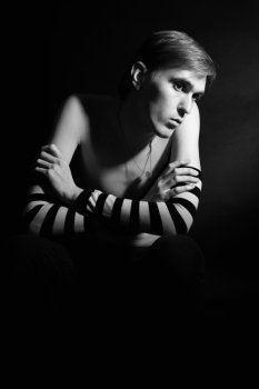 Black and white portrait of a young lonely man on a black background