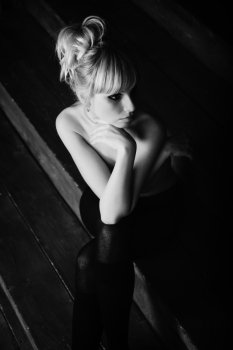 Young beautiful naked woman sitting on wooden stairs