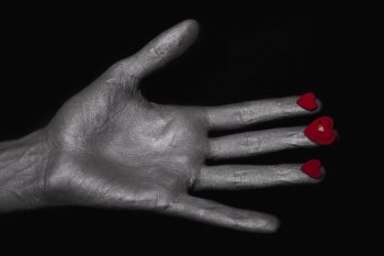 silver man’s hand with a heart symbol on his fingers
