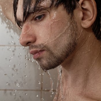 Portrait of a young handsome man takes a shower closeup