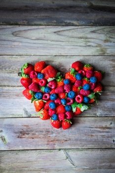 Heart of berries on wooden background