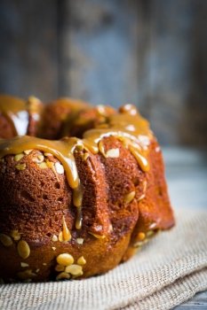 Homemade autumn cake with pumpkin seeds and caramel on wooden background