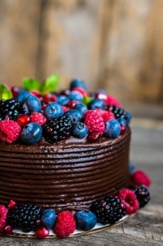 Chocolate cake with berries on wooden background