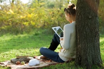 Distance education. Sitting woman using ipad during stroll outdoors