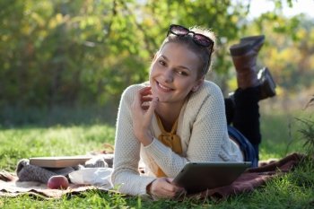 smiling woman lying on bedding with ipad during fun outdoors