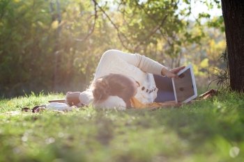 Lying woman watching in ipad screen during rest in the park in evening