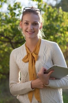closeup of happy woman in glasses with tablet pc in hands in the park