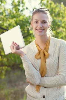Happy young woman holding an ipad outdoors