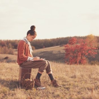 Hipster girl drawing in the fall outdoors