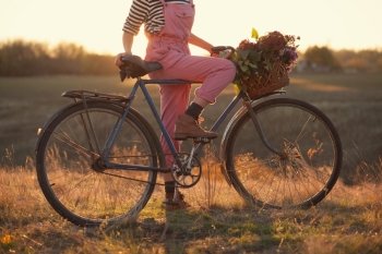 Oldfashioned girl and bike at sunset
