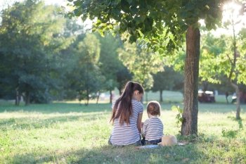 Mother and toddler sitting under the tree during summer  vacation