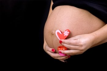 young pregnant woman belly, on a black background
