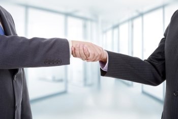 two businessmen in a handshake, at the office