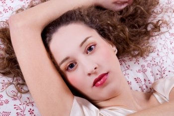 young beautiful woman lying in bed, studio picture