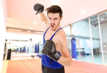 Man punching with black boxing gloves at the gym