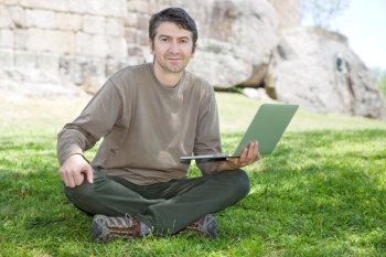 man sitting on the grass working on a laptop