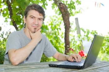 man sitting outdoor working with a laptop