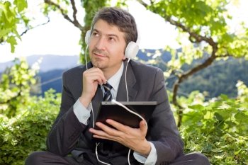 happy businessman with digital tablet and headphones, outdoors