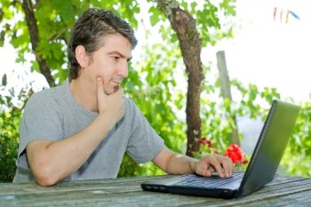 man sitting outdoor working with a laptop