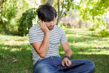 young man relaxing with a tablet pc and phone on a the park, outdoor