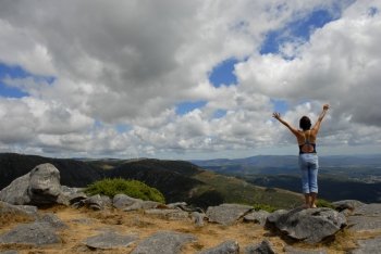 young woman with arms wide open at the mountains