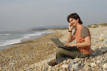 young man at the beach with laptop