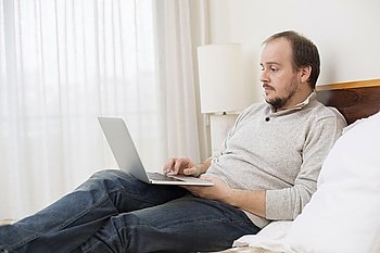 man in bed working with a laptop