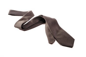 A black tie with white dots is situated semi folded in a zick zack way on a white isolated background