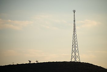 A mobile phone tower stand on a hill in the distance.