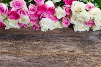 pink and white  roses . fresh pink  and white roses border on wooden table 