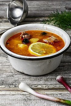Dish of Russian cuisine-beef stew. Traditional solyanka with smoked meat products in the iron bowl