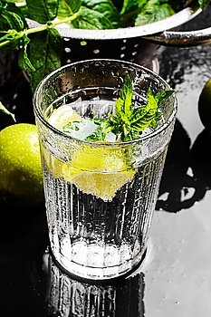 Drink with lime and mint. Glass cup with drink of water with lime in a light background