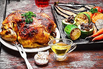 Dish with roast duck. Chicken cooked in vegetables on vintage wooden surface