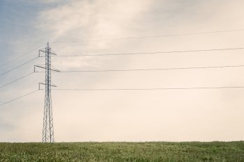 Tall pylons with wires on a green field