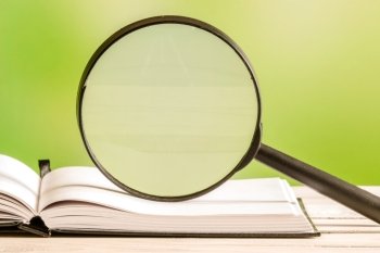 Magnifying glass on an open book with green background