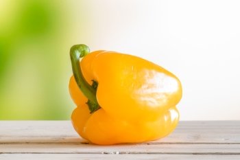 Yellow pepper on a wooden table in a garden