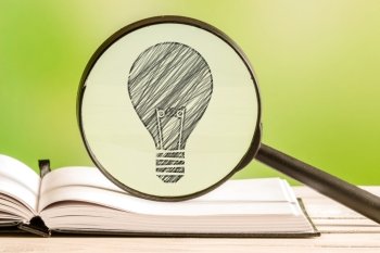 Idea search with a pencil drawing of a light bulb in a magnifying glass