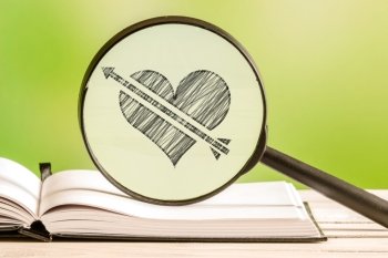 Love search with a pencil drawing of a heart with an arrow in a magnifying glass