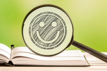 Happiness search with a pencil drawing of smiley in a magnifying glass