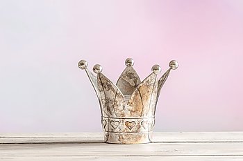 Royal crown on a wooden table on a pink background